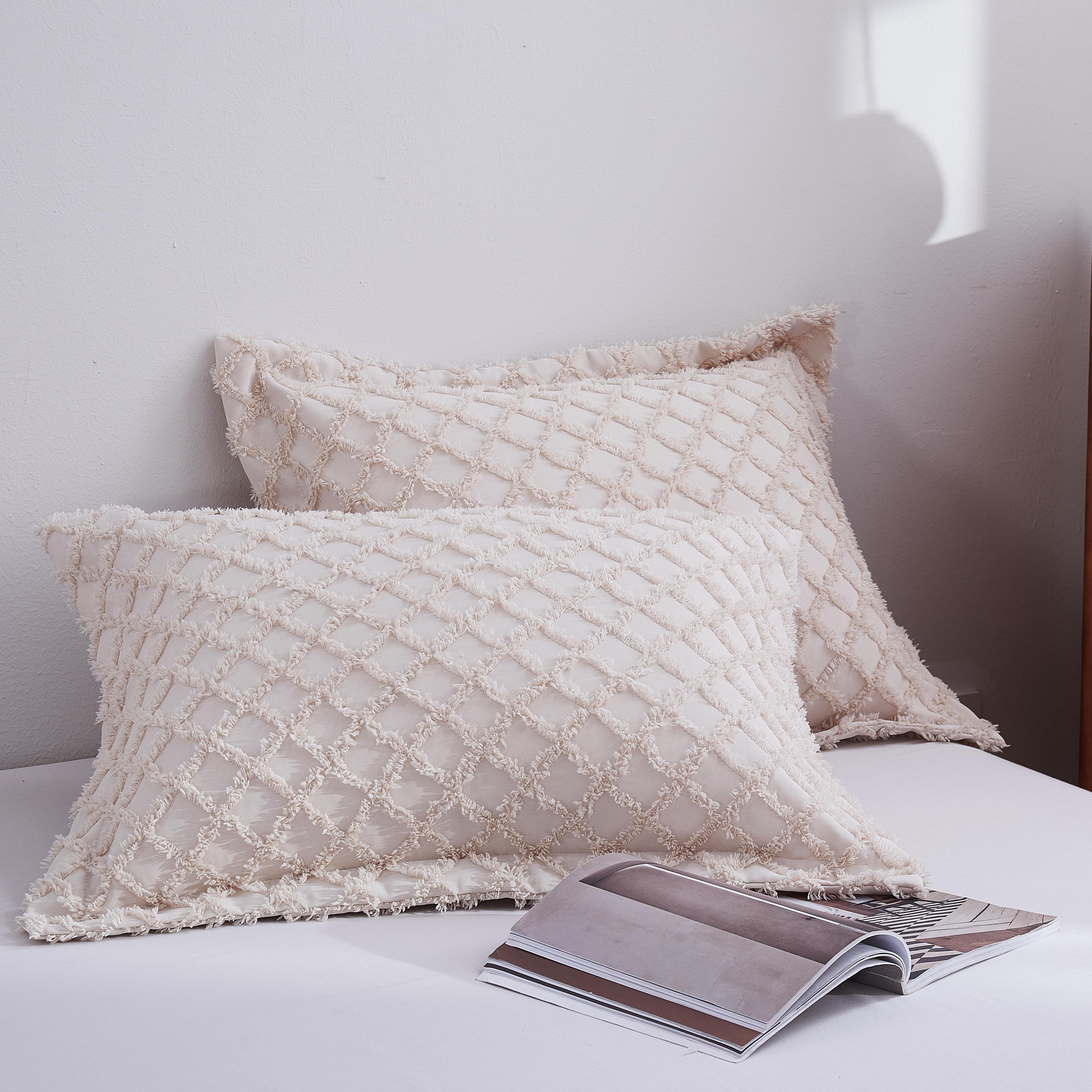 Textured pillows on a bed with a wooden nightstand in the background