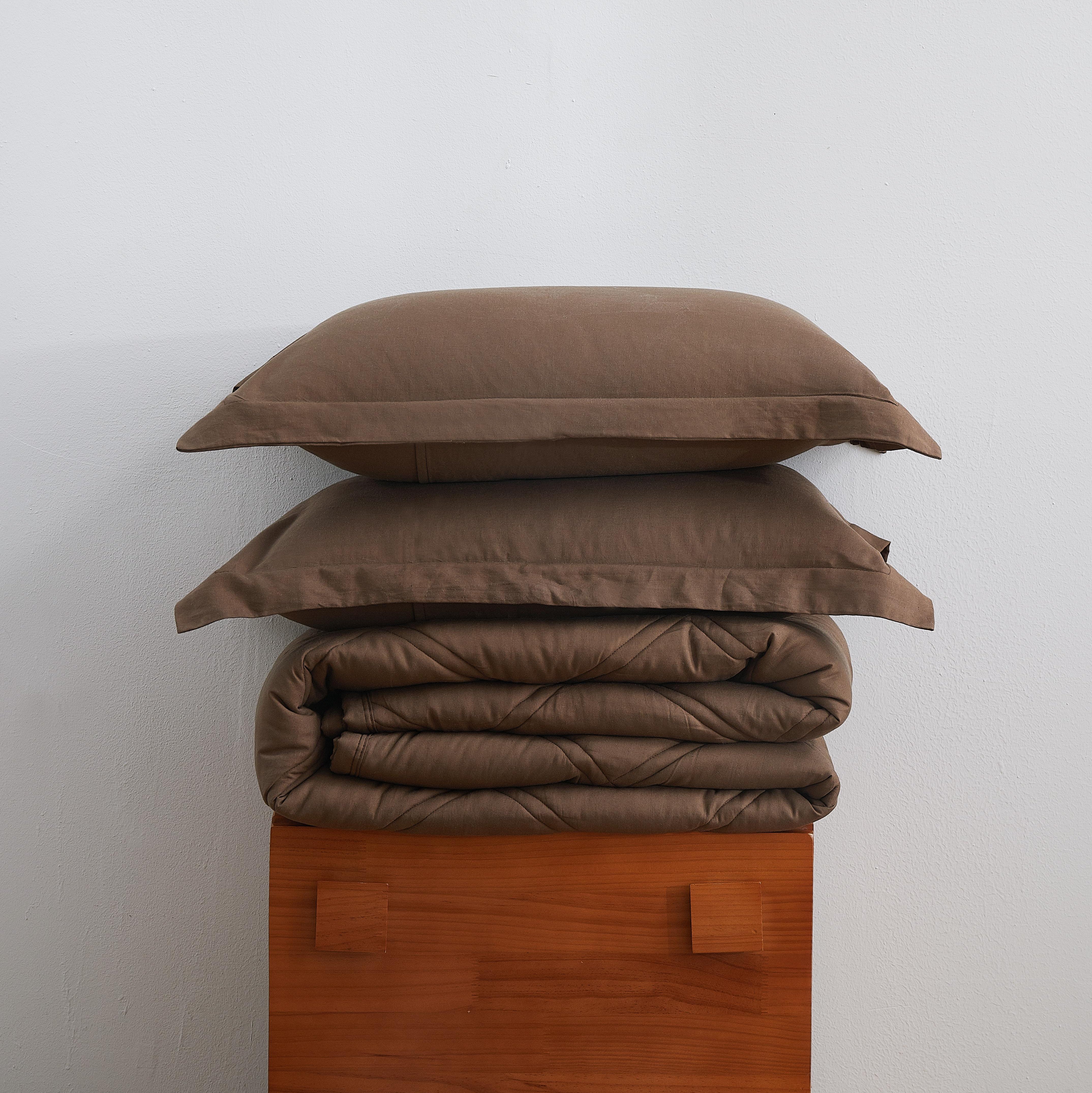 Stack of brown bedding on a wooden block against a white wall