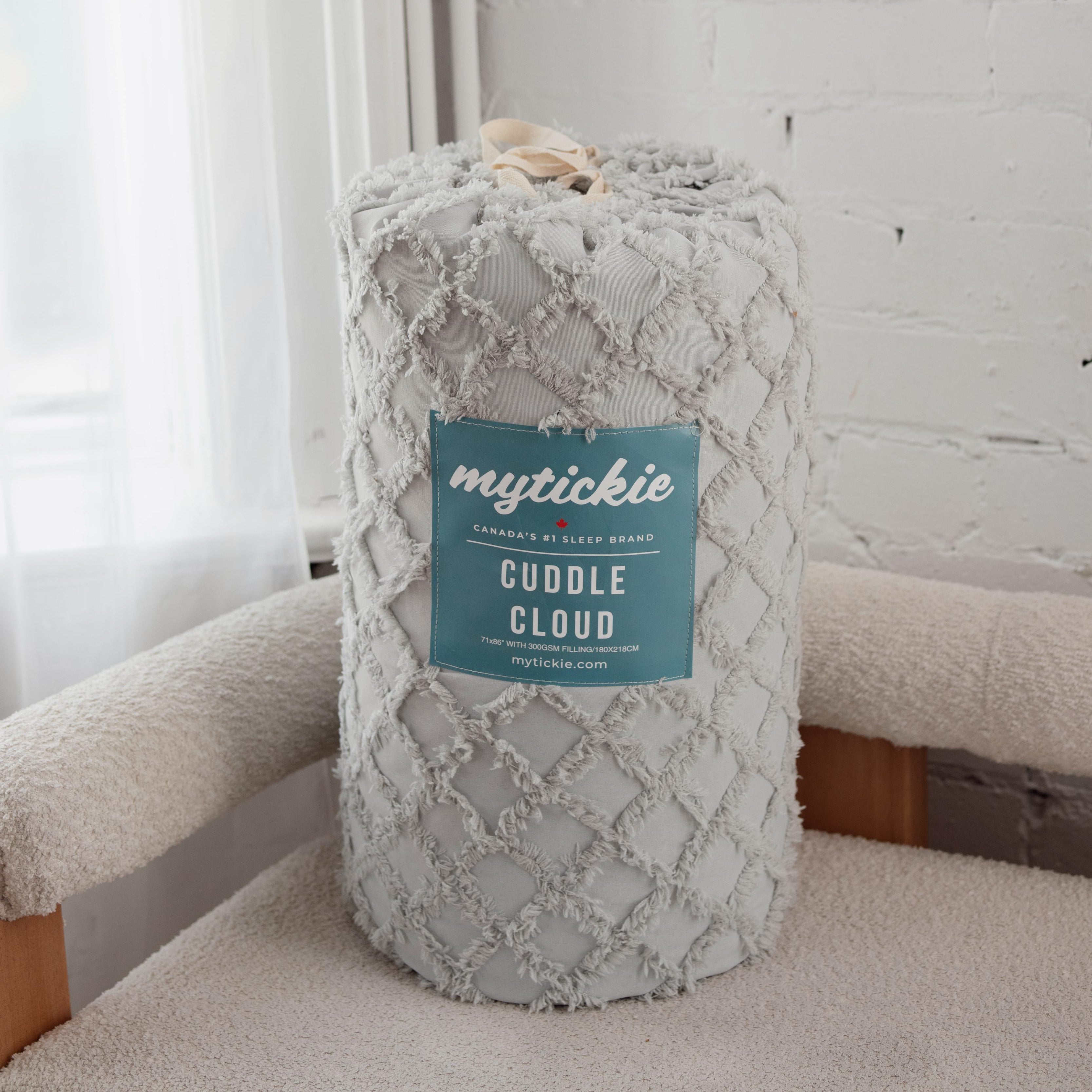 Gray textured blanket with 'mytickie' label on a white couch.