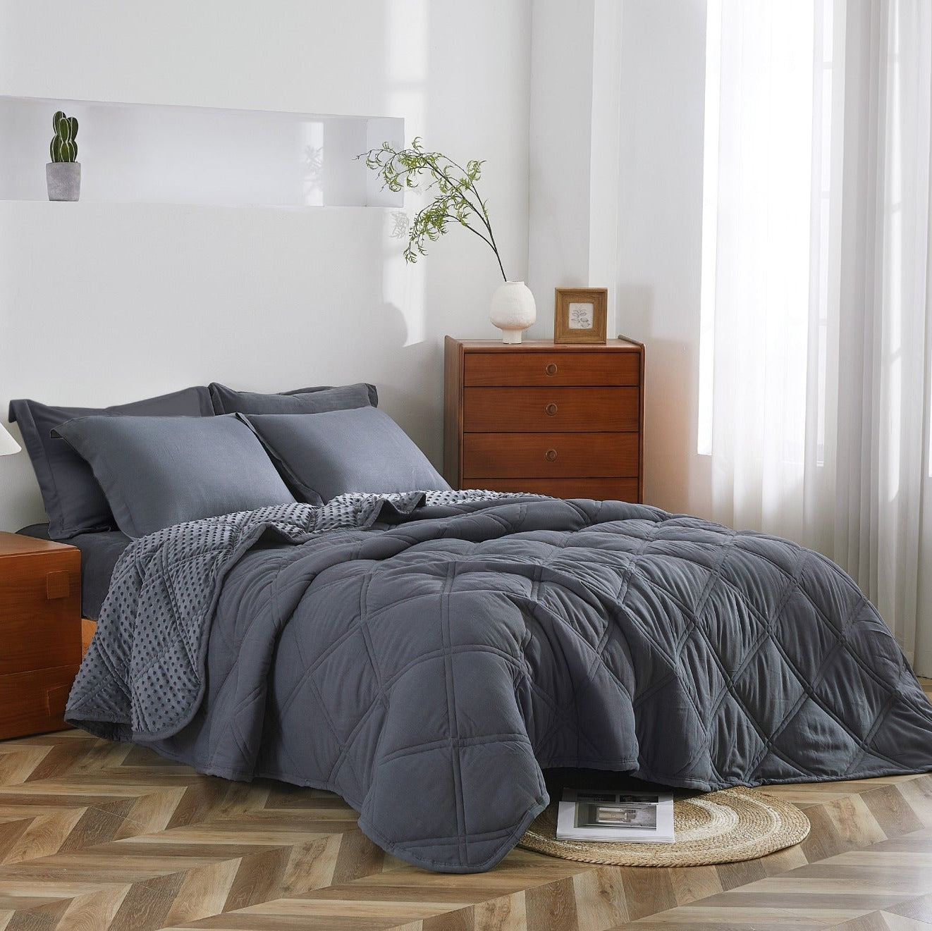 Bedroom with gray bedding on a bed, wooden nightstands, and decorative items.
